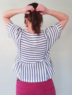 a woman with her hands on her head and wearing a striped top over her shoulders