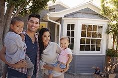 a man, woman and two children standing in front of a house