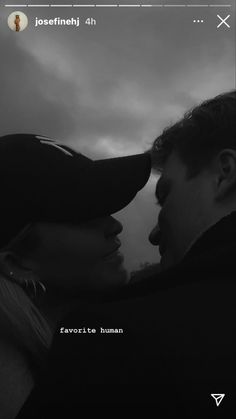 a man and woman standing next to each other in front of a dark cloudy sky