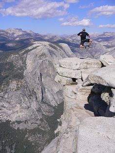 a man standing on the edge of a cliff with his feet in the air,