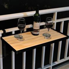 two wine glasses sitting on top of a wooden table next to a bottle of wine