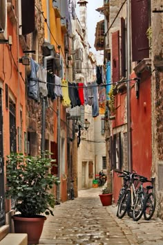 an alley way with clothes hanging from the line and bicycles parked on the side walk