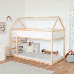 a child's bed with a wooden frame and white mattress in the corner, next to a stuffed animal