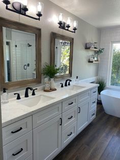 a large bathroom with two sinks, mirrors and bathtub in the middle of it