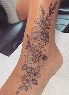 a woman's foot with flowers and leaves tattoo on the side of her leg