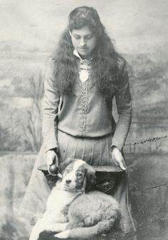 an old black and white photo of a woman holding a dog