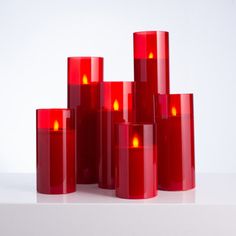 several red candles are stacked on top of each other in front of a white background