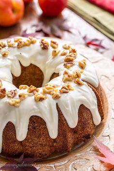 a bundt cake with white icing and walnuts on top sitting on a plate