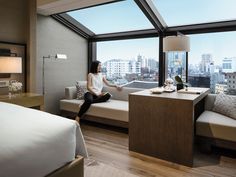 a woman sitting on a window seat in a hotel room with a view of the city