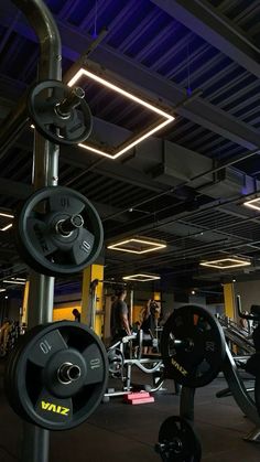 a gym filled with lots of machines and people doing exercises in the background is a blue light