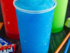 three different colored drinks sitting on top of a table next to candy bars and chopsticks