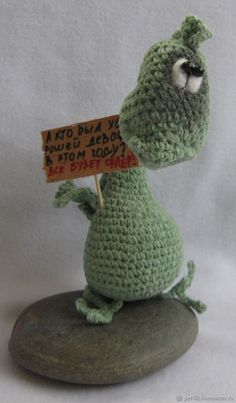 a crocheted stuffed animal holding a sign on top of it's head