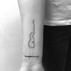 a black and white photo of a guitar tattoo on the left inner arm, with an arrow in the middle