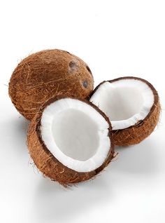 two whole coconuts sitting next to each other on a white surface