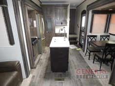 the kitchen and living area of a travel trailer with wood flooring, cabinets, and dining table