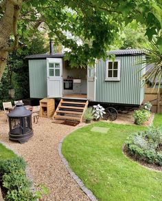 an outdoor kitchen and dining area in a garden with wooden steps leading up to it