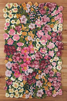 a rug with flowers on it sitting on top of a wooden floor in front of a wall