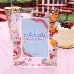 a pink table topped with a cake covered in confetti