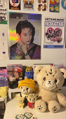 two teddy bears sitting next to each other on a desk with pictures and posters behind them