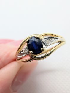 A stunning oval cut blue sapphire gemstone is set in a four claw setting crafted in 14ct yellow gold. A round brilliant cut diamond is set on each side of the sapphire in a white gold mount to enhance the shine of the diamonds. The 14ct yellow gold band is stamped 585.  UK Size P 1/2 US Size 7 3/4 Dimensions: 1.8mm band Sapphire: 4.9mm x 3.8mm Face of ring: 7.9mm  Weight: 2.37 grams This ring is in great condition with general wear and tear associated with a vintage item. Please check images for Oval Blue Sapphire Ring With Diamond Accents, Oval Sapphire Diamond Ring In 14k Gold, Blue Oval Birthstone Ring With Diamond Accents, Gold Oval Sapphire Birthstone Ring, Gold Sapphire Birthstone Ring, Oval Shape, Oval Sapphire Ring In Stamped 14k White Gold, Oval Blue Sapphire Ring In 14k Gold, Oval Yellow Gold Sapphire Ring With Diamond Accents, Oval White Gold Sapphire Ring In 14k