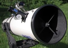 a white and black telescope sitting in the grass