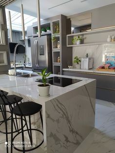 a kitchen with white marble counter tops and black bar stools next to an island