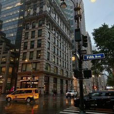 a yellow taxi cab driving down a street next to tall buildings in the city at night