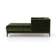 a green couch sitting on top of a white floor next to a wooden legrest