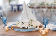 a small sailboat with flowers and candles is on the centerpieces at this wedding reception