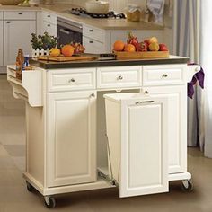 a white kitchen island with two trash cans on it's wheels and fruit in the middle