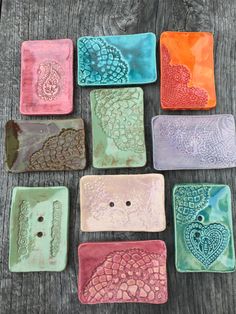 nine ceramic coasters in different colors and designs on a wooden table with a wood background