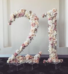 a large number made out of flowers sitting on top of a floor next to a window