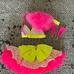 two swimsuits are laying on the floor with pink and yellow accessories around them