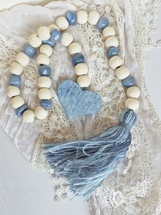 a tasseled necklace with blue and white beads on top of a lace doily