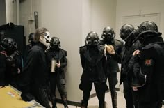 several people wearing gas masks and holding bananas in front of a mirror while standing next to each other