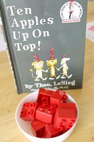 red legos are in a white bowl next to a book about apples on top