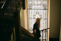 a woman is standing at the top of stairs in front of a stained glass window