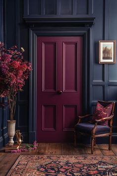 a purple door in a blue room next to a chair and vase with pink flowers