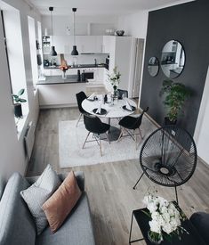 a living room filled with furniture and a white table surrounded by black chairs on top of a hard wood floor