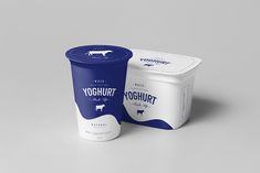 two yogurt containers sitting next to each other on a gray surface, one is blue and the other is white