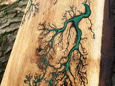 a piece of wood that has been carved with green paint on it and is next to a tree