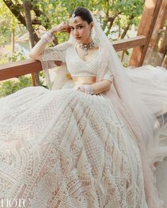 a woman in a wedding dress sitting on a bench with her hands behind her head