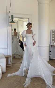 a woman standing in front of a mirror wearing a white dress