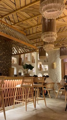 the interior of a restaurant with wooden tables, chairs and chandeliers hanging from the ceiling