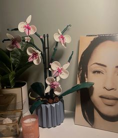 an arrangement of flowers, candles and pictures on a shelf next to a candle holder