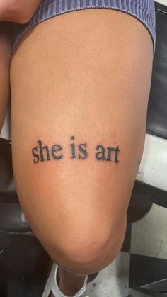 a woman's thigh with the words she is art tattooed on it