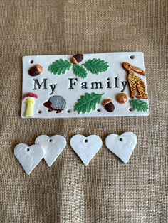 three ceramic ornaments with the words, my family on them and pine cones in the shape of hearts