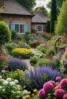 a garden filled with lots of flowers next to a house