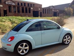 a small blue car parked in front of a building on the side of a road