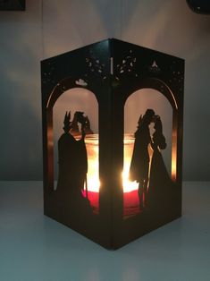 the silhouettes of two people are shown in this paper cut out box that is lit up